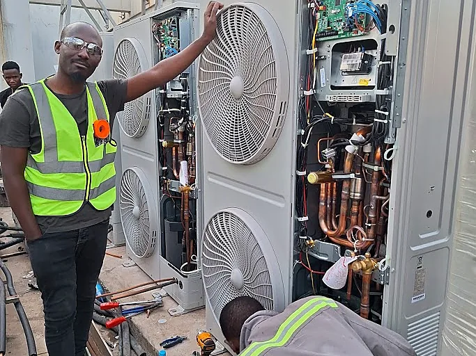 Technicians inspecting a commercial VRF outdoor unit